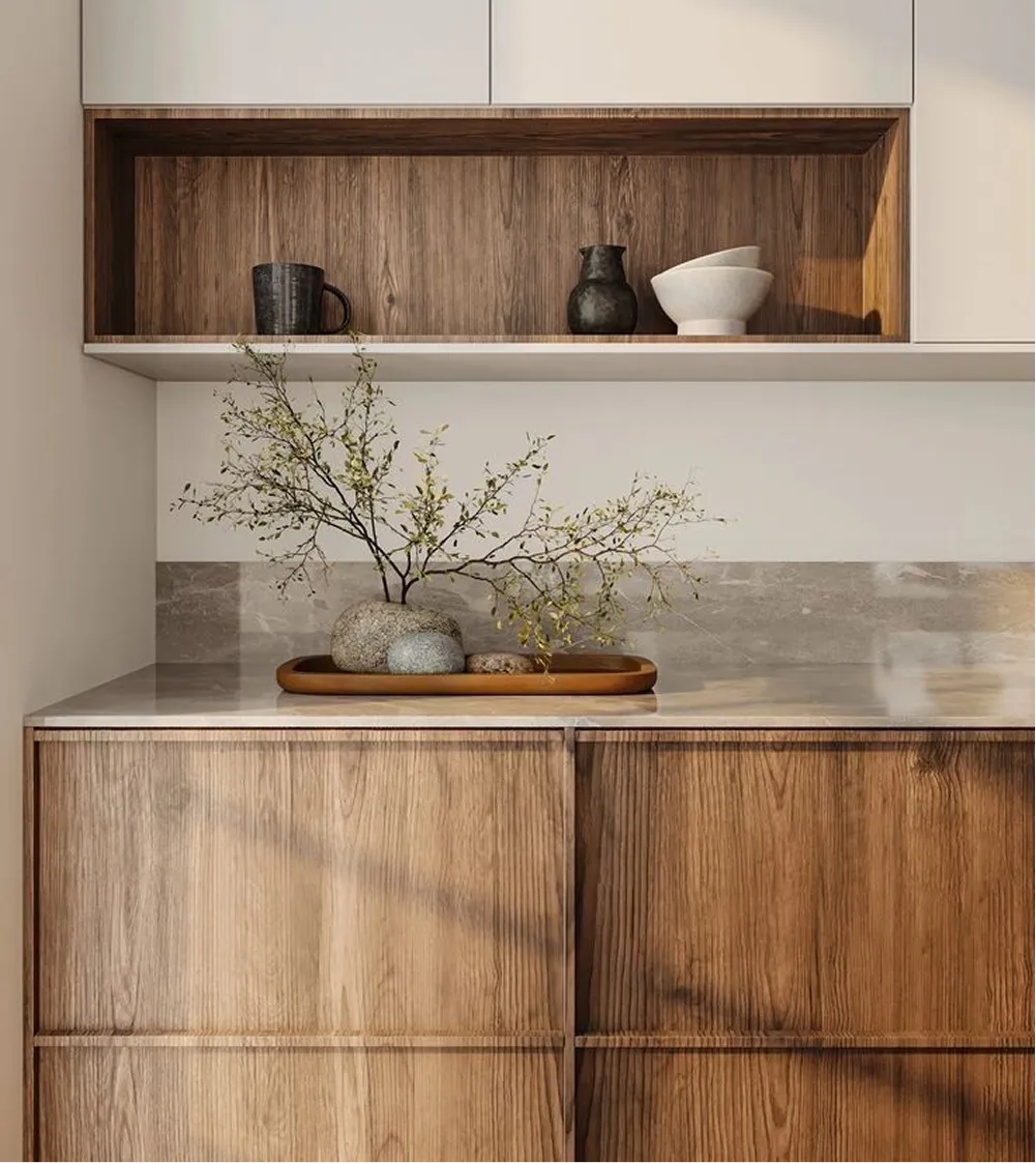 Walnut cabinets with an open niche holding hand thrown ceramics above a honed stone worktop.