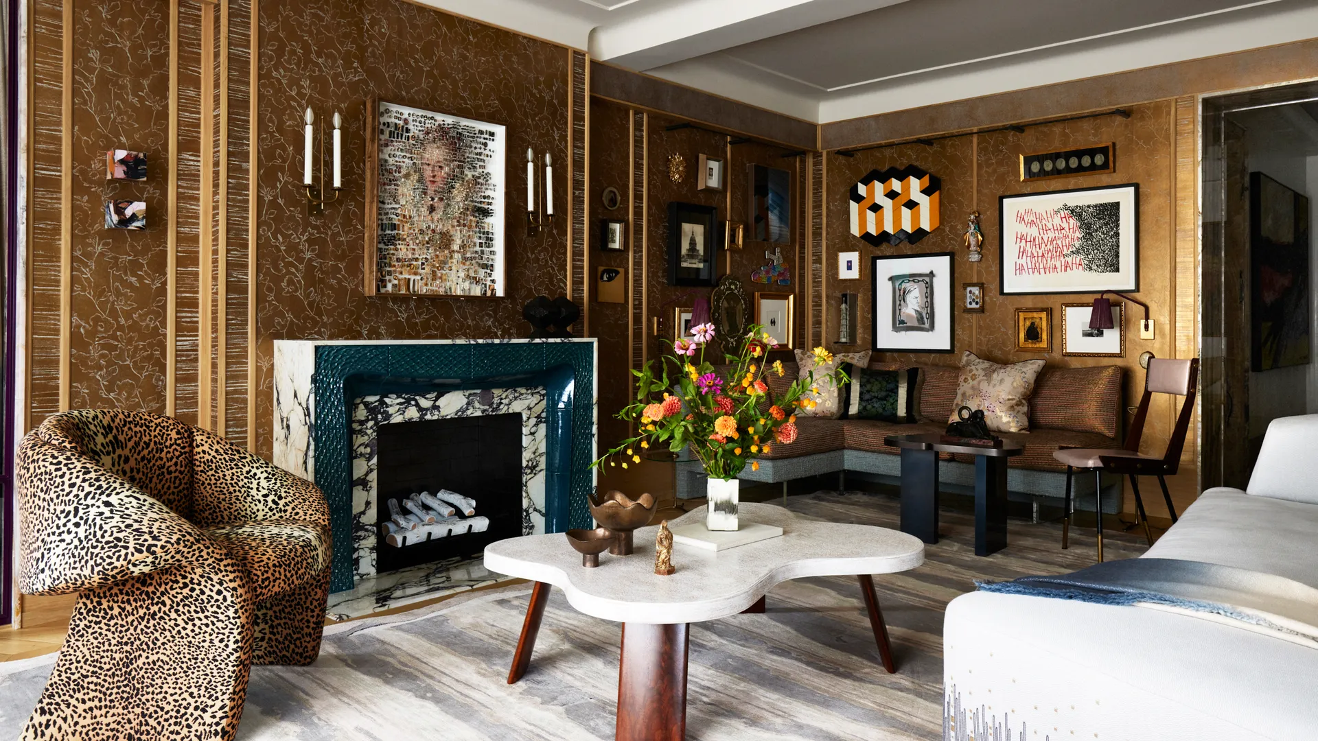Living room with textured bronze walls, a marble fireplace trimmed in green, a leopard print armchair and a sculptural cream coffee table.