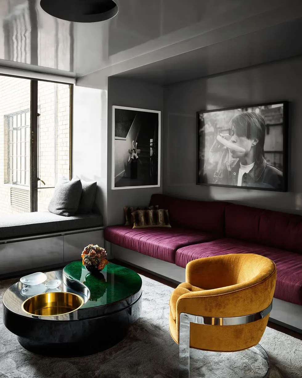 Sitting room with a low plum velvet sofa, a mustard velvet chair banded in chrome and a black lacquered table with brass and malachite.