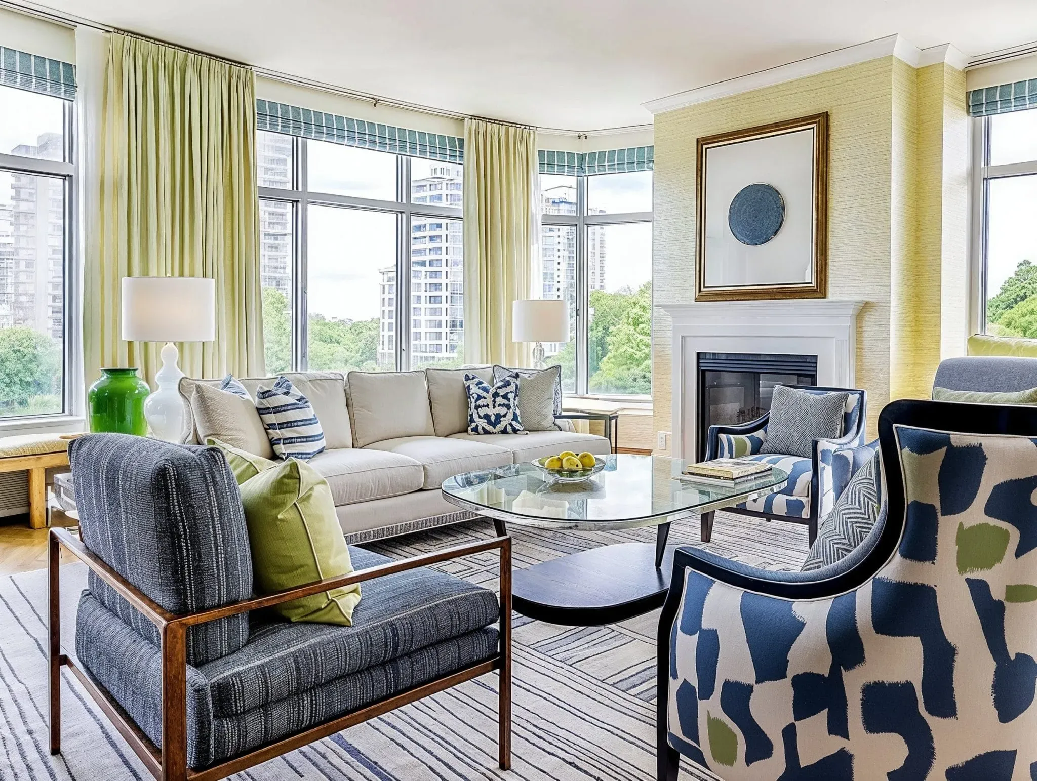Apartment living room with a cream sofa, a glass topped coffee table, patterned armchairs in navy and green and tall windows over the city.