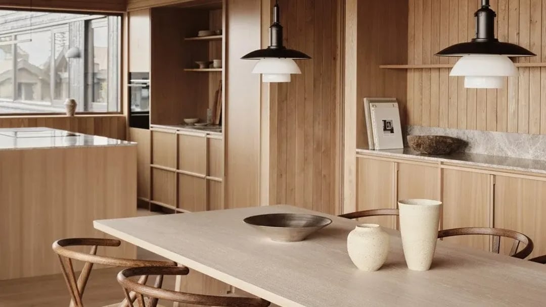 Oak kitchen with a marble worktop run, an island with an induction hob and two pendant lights over the dining table.