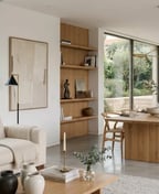 Open plan living and dining room with a cream sofa, an oak dining table with woven chairs and full height glazing.
