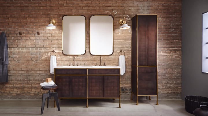 Double vanity with two basins and a tall column in dark wood, two brass-framed mirrors and wall lights either side