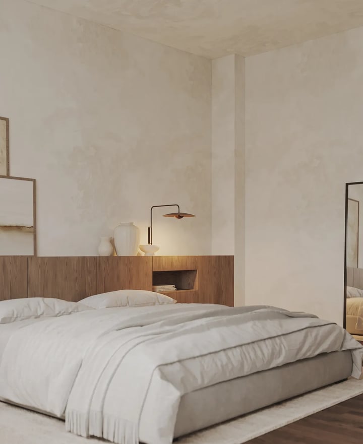Low grey upholstered bed in front of a wooden headboard panel with a lit niche, a lamp and a full-length mirror
