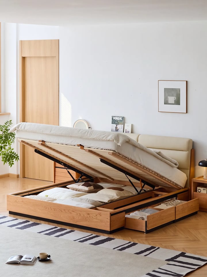 Wooden double bed with its base raised on gas pistons, pillows in the storage well and side drawers pulled open