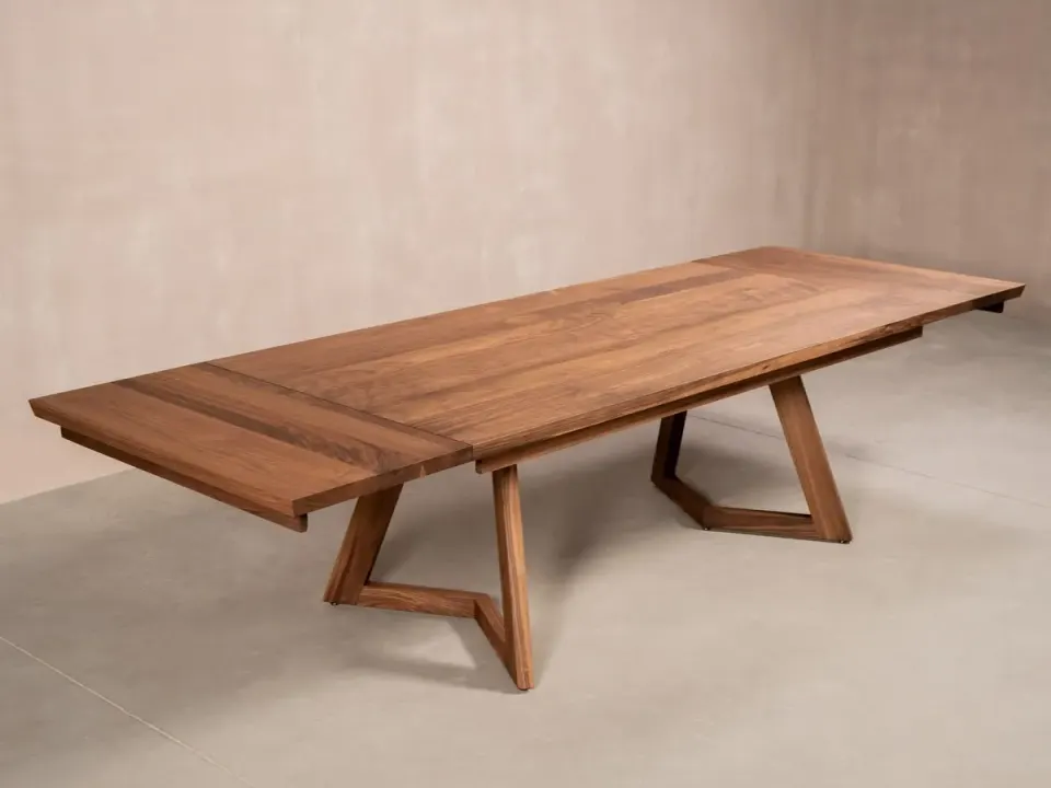 Long walnut dining table with both end extensions pulled out, on two angular walnut supports